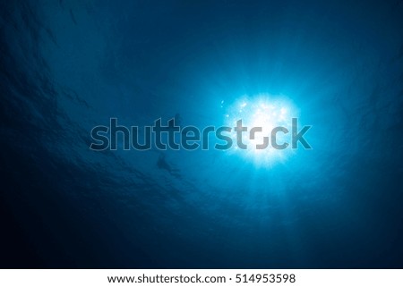 Sunburst and silhouette of divers underwater