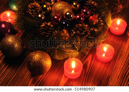 Christmas arrangement. Fir wreath, Christmas balls, burning candle. Photos shot in a dark key. Photo toned. Soft focus.
