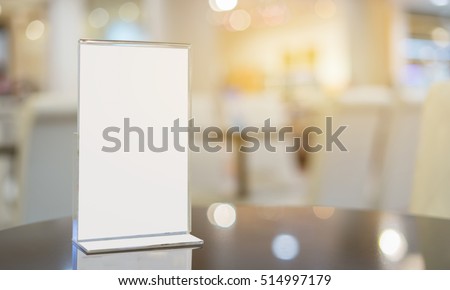 Mock up Menu frame on Table in Bar restaurant ,Stand for booklets with white sheets of paper acrylic tent card on cafeteria blurred background

