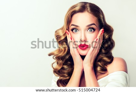 Woman surprise holds cheeks by hand .Beautiful girl  with curly hair  pointing to looking right . Presenting your product. Isolated on white background. Expressive facial expressions Royalty-Free Stock Photo #515004724