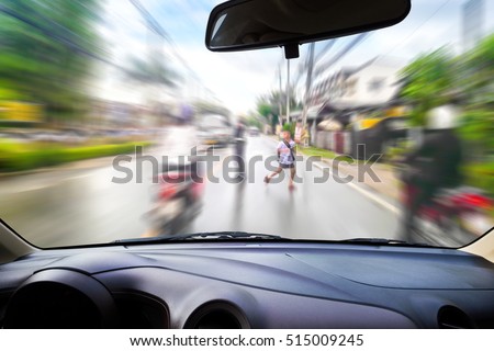 In the car, motion blur image of children running across the street as background.