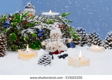 Christmas still life is with snow. Toy Santa Claus is sitting under a Christmas tree. 