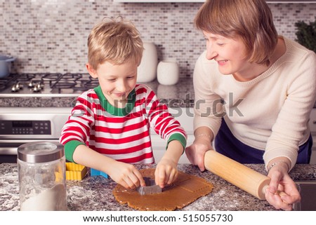 family of two baking gingerbread cookies at home at christmas time, holiday concept
