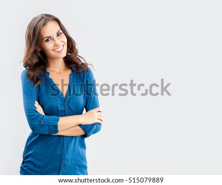 Happy smiling young businesswoman, on grey background. Caucasian brunette model in business concept studio shoot. Blank copyspace area for advertise text or slogan.