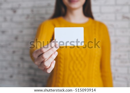 Hipster young woman holding a mock-up blank business card and smiling
