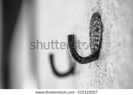Closeup of black iron hook for clothes on wall black & white 