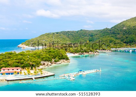 Beach and tropical resort, Labadee island, Haiti. Exotic wild beach with palm and coconut trees against blue sky and azure water Royalty-Free Stock Photo #515128393