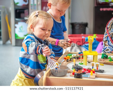 Children playing with wooden train. Toddler boy and baby girl play with crane, train and cars. Educational toys for preschool and kindergarten child. ?ute kids build toy railroad at home or daycare. Royalty-Free Stock Photo #515137921