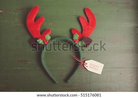 Christmas Reindeer Ears with Happy Holidays gift tag on a rustic distressed wood background, with applied retro style filters. 