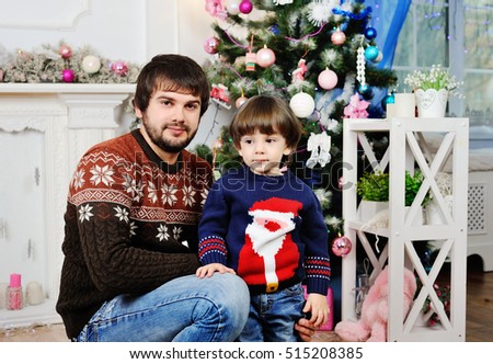 father and son in a warm sweater sitting on the background of the Christmas tree in the studio