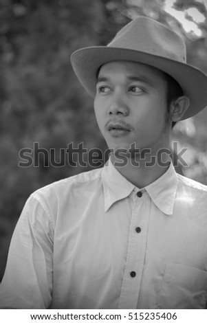 Portrait of a smart asian young man with brown hat and nature background
