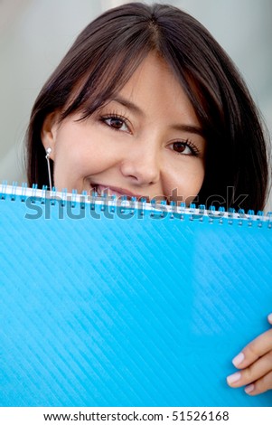 Female student holding a notebook and covering half her face