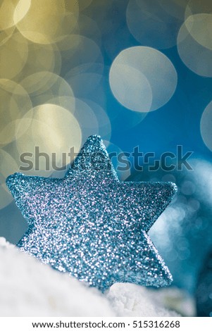 Christmas ball and star on snow and gold glitter on blue background. 