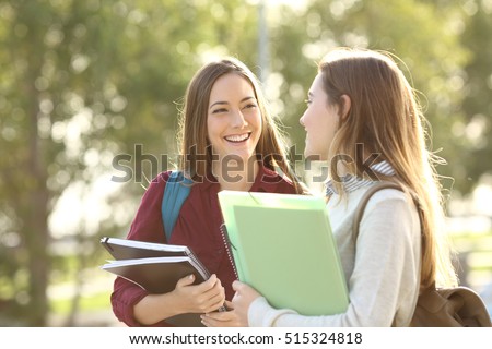 Two happy students walking and talking each other in a campus at sunset with a warm light Royalty-Free Stock Photo #515324818