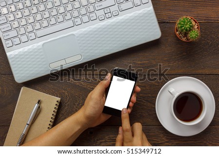 Top view business man using mobile phone and coffee, laptop,notebook,cactus on wooden office desk.