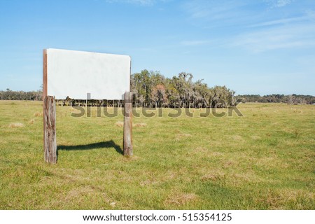 Blank white sign in a rural field on a sunny day