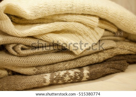 Stack of cozy knitted sweaters on a wooden table. Retro style. Warm concept