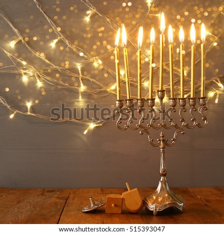 Low key Image of jewish holiday Hanukkah with menorah (traditional Candelabra) and wooden dreidel (spinning top). Vintage filtered