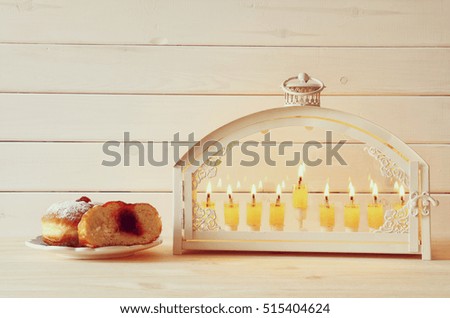Selective focus image of jewish holiday Hanukkah with menorah (traditional Candelabra) and donuts