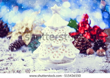 Snow Falling On Beautiful Setting For Christmas With Tree Candle On Snowy Wooden Background With Decor. Selective Focus. Vintage Filter Applied.