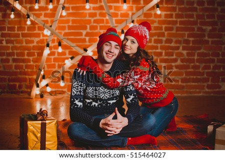 Happy loving young people having fun near the Christmas tree. Smiling couple celebrating New Year. Toned image.