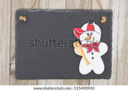 Old fashion Christmas hanging chalkboard background for a baseball fan, A retro chalkboard with baseball snowman hanging on weathered wood background with copy space for your message