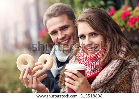 Picture showing young couple on date in the city with coffee and donuts