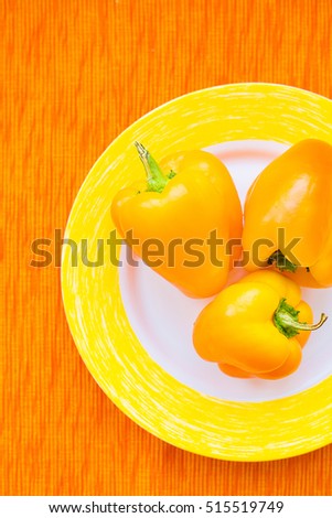 Three bright yellow peppers on a plate close up