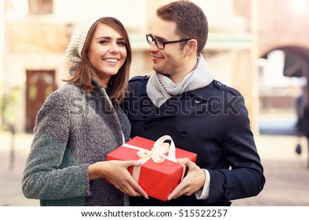 Picture showing young couple with big present in the city