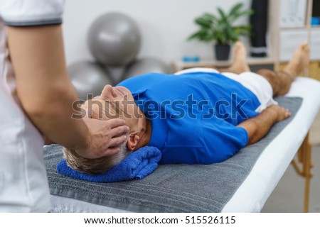 Male physiotherapist giving head massage a senior patient in clinic Royalty-Free Stock Photo #515526115