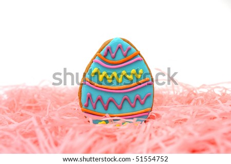 Close up of easter egg cookie on pink ribbons over white background.