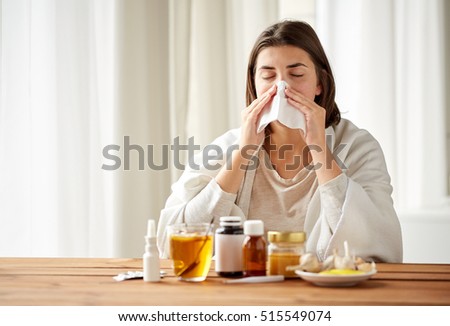 health care, flu, hygiene, age and people concept - sick woman with medicine blowing nose to paper wipe at home Royalty-Free Stock Photo #515549074