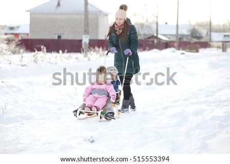 Happy young woman with two children on a sled on winter walk