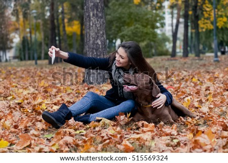 young girl with a brown labrador in the autumn park, make selfie photo