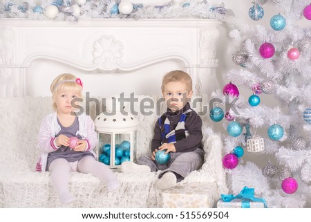 Little boy and girl sitting on the background of the Christmas tree