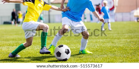 Football soccer match for children. Boys playing football game on a school tournament. Dynamic, action picture of kids competition during playing football. Sport background image.