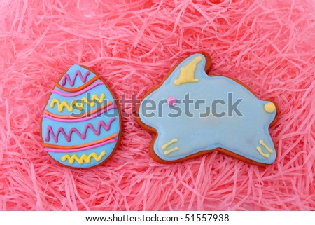 Close up of easter egg and bunny cookies on pink ribbons as background.