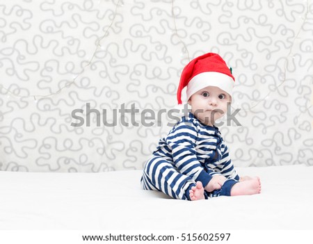 wondered baby boy wearing a crocheted Santa hat on light background, selective focus