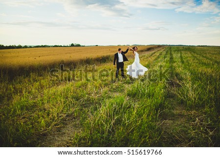 happy and young bride and groom dancing in the field