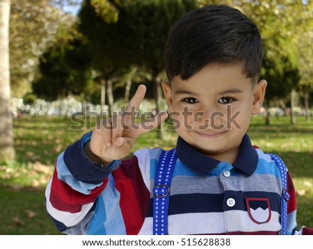 Smiling young little boy gives a Victory Sign
