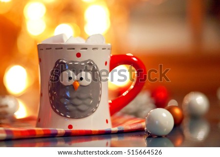 A cup with an owl, in which coffee and marmelshou. Christmas star with lights and toys for the Christmas tree.