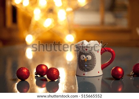 A cup with an owl, in which coffee Christmas star with lights and toys for the Christmas tree.