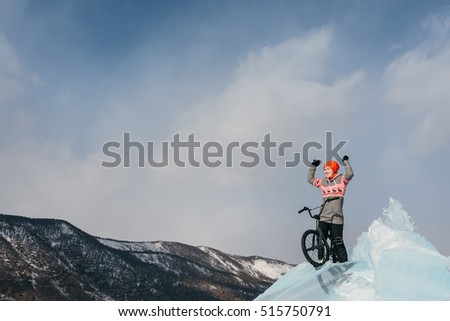 Girl standing on a bmx on the beautiful and dangerous ice and enjoys a successful campaign. Ice the deepest lake in the world. This is Lake Baikal.