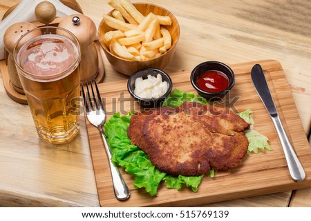 Schnitzel with fries and beer on wooden background