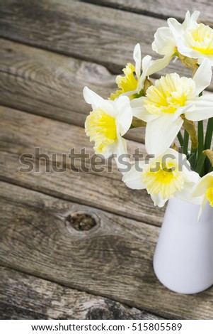 white daffodils at china vase on old weathered wood table