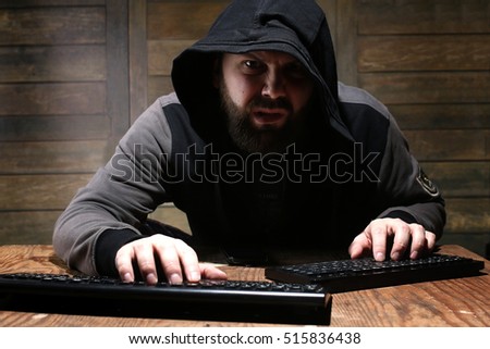 hacker in the black hood in a room with wooden walls
