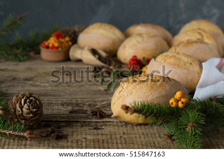 bread bun on wooden table decorated with tree branches pine cones and decorative berries