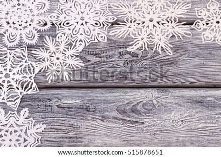 Snowflakes on grunge wooden background. Openwork snowflakes from white paper on a gray wooden background.