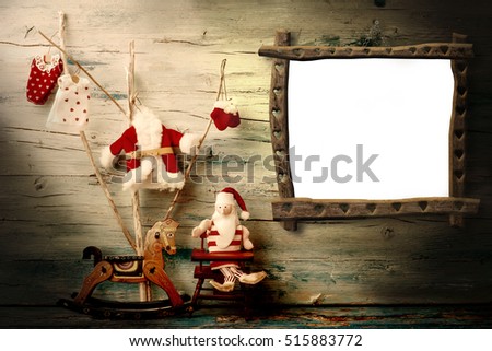 Christmas photo frame greeting card. Santa, tree and rocking horse with blank frame hanging on wooden wall