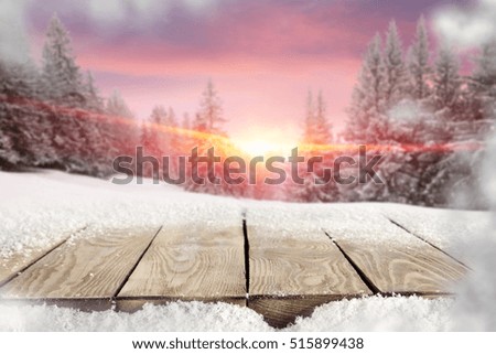 Old wooden table with sparkling snow of free space for your decoration. Landscape of mountains with great snow-covered trees, the sun during the golden hour, and a beautiful pink sky December. 